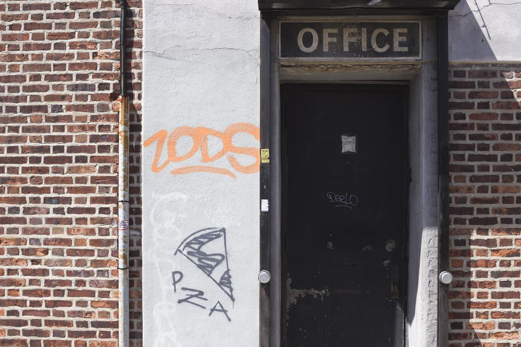 A wall with various textures, graffiti reading “Zods” and sign reading “OFFICE”.