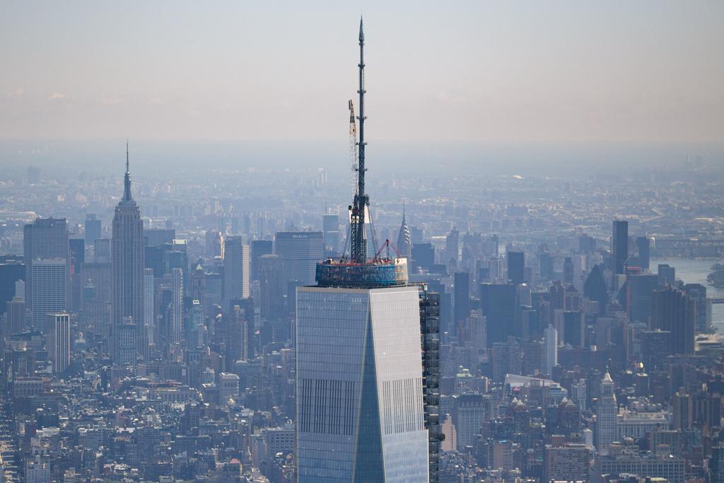 The top of the under construction One world trade center building. The Empire State and Chrysler building are also notable in the background.