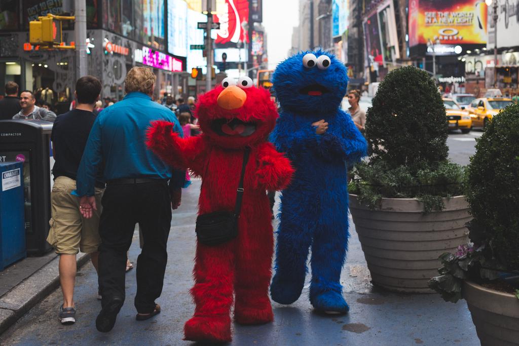 Sesame Street characters Elmo and Cookie monsters approaching me with open arms in Times Square.