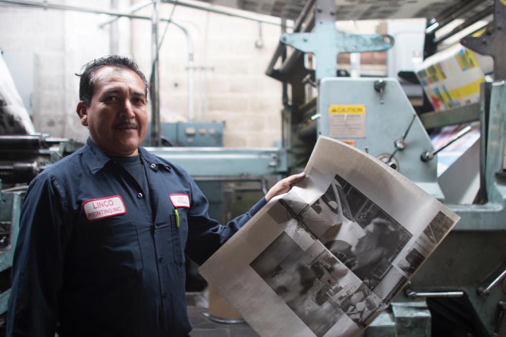 An employee of Linco printing holding the newspaper.